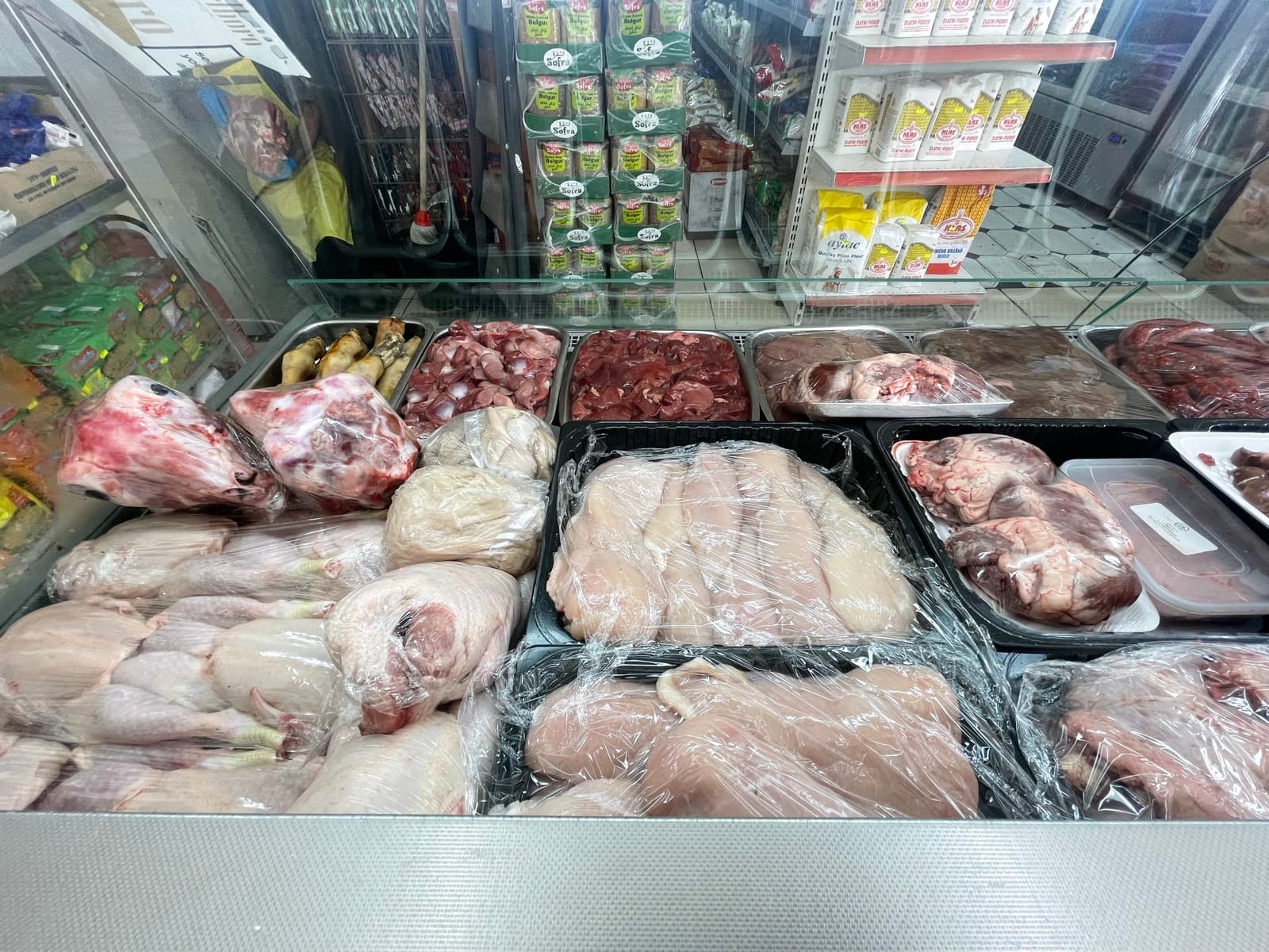 The refrigerated butchery counter with trays of lamb, beef and poultry and a handwritten price board