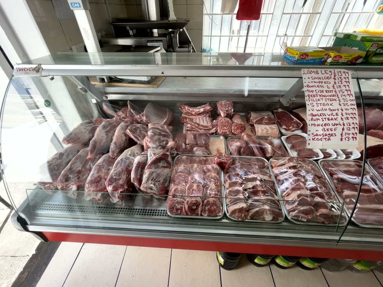 Footage filmed along the refrigerated butchery counter, showing trays of lamb and beef behind glass